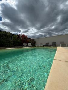 una piscina bajo un cielo nublado con sillas en Villa 1 Les Maisons dans les Vignes, en Joyeuse