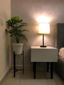 a table with a lamp and a potted plant on it at Elysium Tower Studio Apartments with Centaurus View, Islamabad by LMY in Islamabad