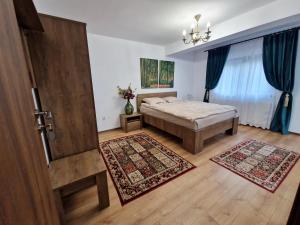 1 dormitorio con cama y puerta con alfombras en Pensiunea Izvorul Liniștii 