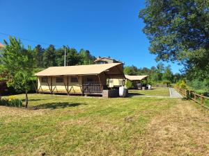 a large building with a roof on a grass field at Quinta do Rio Alva and Glamping Lodges in Mouronho