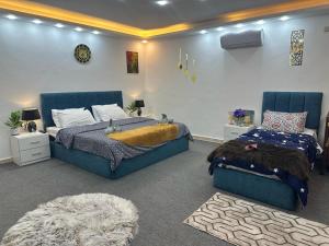 a bedroom with two blue beds and a rug at Jerash City View in Jerash