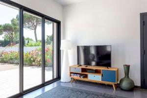 a living room with a tv and a large window at Chez Diane - Luxueuse Villa avec piscine et plage à proximité in La Grande-Motte