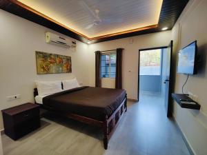 een slaapkamer met een bed en een flatscreen-tv bij Kevin's House by TravelKrafts in Anjuna