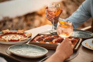 una mesa con platos de comida y una copa de vino en Lago Resort Menorca - Casas del Lago Adults Only, en Cala'n Bosch