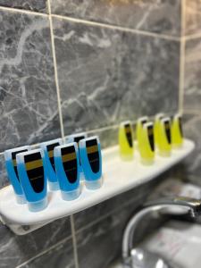 a row of blue and yellow cups on a shelf in a bathroom at Pyramids Hills INN in Cairo