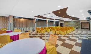a room with yellow chairs and tables and a checkerboard floor at Treebo Trend Dream Palace in Jaipur
