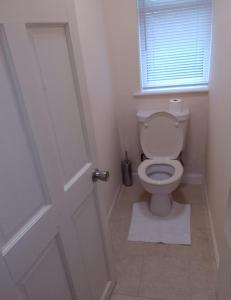 a bathroom with a toilet with a window and a door at Solihull Guest House 1 in Olton