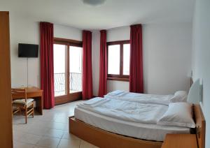 Locanda Bellavista food&rooms في مالسيسيني: غرفة نوم بسرير كبير مع ستائر حمراء