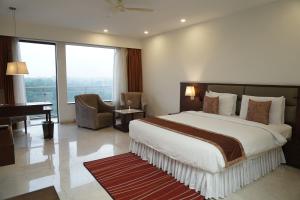 1 dormitorio con 1 cama grande y piano en The Alcor Hotel, en Jamshedpur