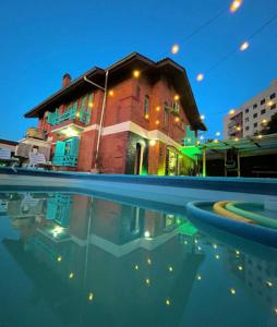 una casa con una piscina d'acqua di fronte a un edificio di Casa do Rogério Hostel a Caxias do Sul