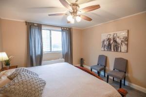 a bedroom with a bed with a ceiling fan and two chairs at Downtown Atlanta! Onsite Parking! 24 CONCIERGE LM908 in Atlanta