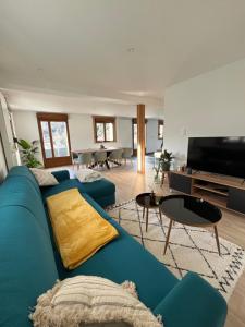 a living room with a blue couch and a tv at Le Balcon de Bramont in La Bresse