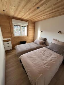 two beds in a room with wooden walls at Le Balcon de Bramont in La Bresse