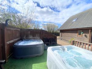 a large hot tub sitting on the grass next to a fence at Lbtie Lodge with Two Private Hot Tubs - Fife - Loch Leven - Lomond Hills in Kelty