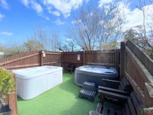 a backyard with a hot tub and a deck with a bench at Lbtie Lodge with Two Private Hot Tubs - Fife - Loch Leven - Lomond Hills in Kelty