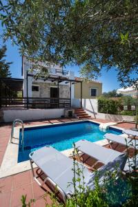 a swimming pool with chairs and a house at Villa Olivia in Chania Town