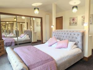 1 dormitorio con 1 cama grande con almohadas rosas en Torridon 1 with Private Hot Tub - Fife - Loch Leven - Lomond Hills- Pet Friendly, en Kelty
