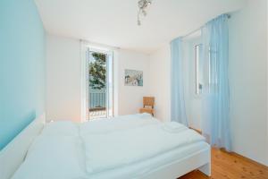 a white bedroom with a bed and a window at Brissago Lake Apartment in Brissago