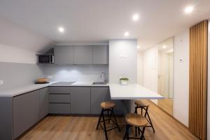 a kitchen with white counters and stools in a room at Apartments BB in Bohinj