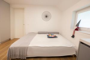 a white bedroom with a bed and a window at Apartments BB in Bohinj