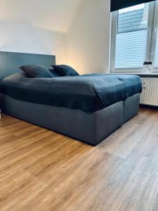 uma cama grande num quarto com piso em madeira em FeWo Burgnest em Bad Bentheim