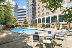 einen Pool mit Tischen und Stühlen vor einem Gebäude in der Unterkunft Downtown Atl Condo Onsite Parking King bed & bonus room LM1901 in Atlanta