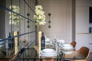 una sala da pranzo con tavolo in vetro, piatti e fiori bianchi di EASY RENT Apartments- CityCenter Place a Lublino