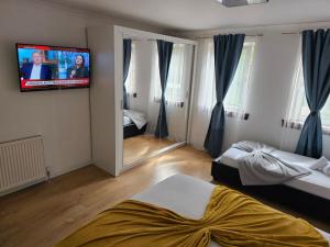 a bedroom with two beds and a tv on the wall at Modern house close to Glasgow Green in Glasgow