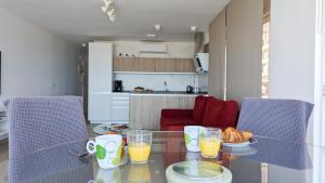 ESMERALDA sea front apartment في بنيدورم: طاولة زجاجية عليها عصير برتقال وكرواسان