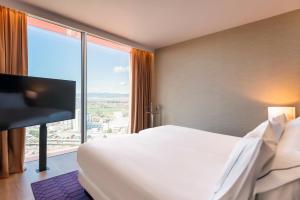 ein Hotelzimmer mit einem Bett und einem großen Fenster in der Unterkunft Hyatt Regency Barcelona Tower in Hospitalet de Llobregat