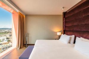 una camera con un grande letto e una grande finestra di Hyatt Regency Barcelona Tower a Hospitalet de Llobregat