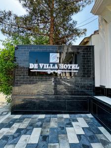 a sign for a villa hotel on a brick wall at De Villa Hotel in Samarkand