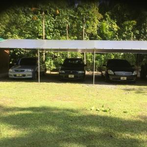 two cars parked under a white canopy in a field at M&A Riverside Beach Bungalows in Chol