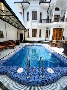 a swimming pool with two faucets in front of a house at De Villa Hotel in Samarkand
