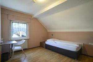 a bedroom with a bed and a desk and a window at Gästehaus Rebstock in Igel
