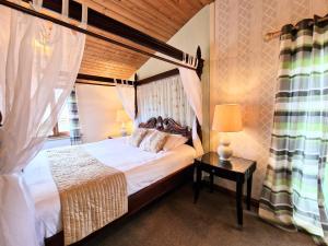 1 dormitorio con cama con dosel y mesa en Lomond 3 with Private Hot Tub - Fife - Loch Leven - Lomond Hills -Pet Friendly, en Kelty