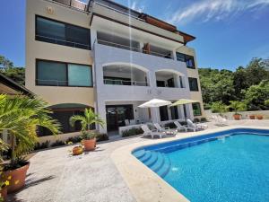 a house with a swimming pool in front of a building at El Tular 2 Bdr Appartment 2 min walk from La Ropa beach in Zihuatanejo