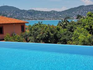 a blue swimming pool with a view of the water at El Tular 2 Bdr Appartment 2 min walk from La Ropa beach in Zihuatanejo