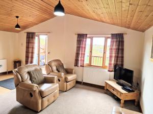 a living room with two chairs and a television at Lomond 3 with Private Hot Tub - Fife - Loch Leven - Lomond Hills -Pet Friendly in Kelty