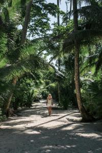 een vrouw die over een pad tussen palmbomen loopt bij M&A Riverside Beach Bungalows in Chol