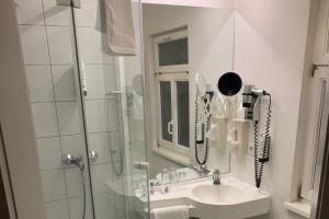 a bathroom with a sink and a shower with a phone at Aspire Kronprinz, Trademark Collection by Wyndham in Schwäbisch Hall