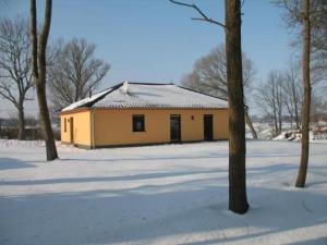 ein gelbes Gebäude im Schnee mit Bäumen in der Unterkunft Ferienhaus für 6 Personen ca 128 m in Sanitz, Ostseeküste Deutschland Landkreis Rostock in Sanitz