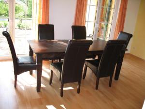 a dining room table with black chairs and a wooden floor at Ferienhaus in ruhiger aber zentraler Lage, mit zwei Terrassen und Garten in Sanitz
