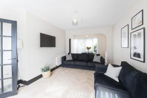 ein Wohnzimmer mit einem schwarzen Sofa und einem TV in der Unterkunft Poppy's Place - Manningham Road in Liverpool