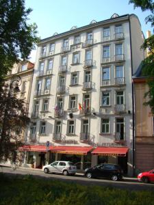 a large white building with cars parked in front of it at Hotel Saint Petersburg in Karlovy Vary