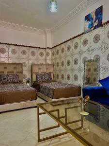 1 dormitorio con 2 camas y mesa de cristal en Dar el omari en Rabat