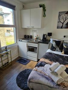 a bedroom with a bed and a kitchen in it at Tiny Studio, 30 min to St. Pancras, North London in London