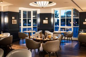 a restaurant with tables and chairs and windows at Hotel Atlantic Hamburg, Autograph Collection in Hamburg