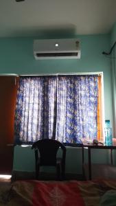 a bedroom with a window with a table and a curtain at Kairali Lodge in Trichūr