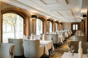 a restaurant with white tables and chairs and windows at Hotel Atlantic Hamburg, Autograph Collection in Hamburg